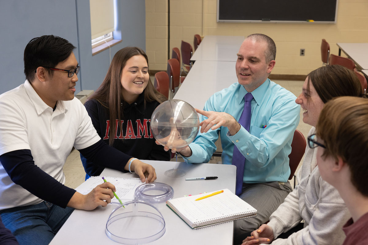Students meeting with their professor working on a math problem