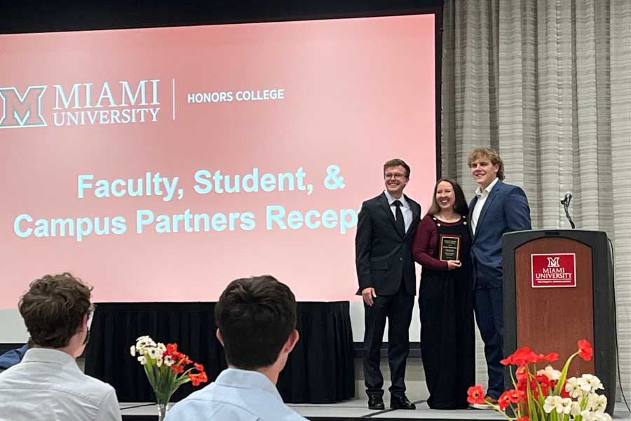 Jen Temmerman presented with a plaque on stage with colleagues