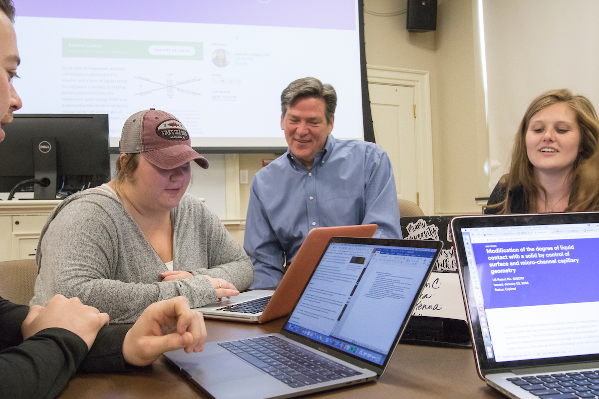 Wayne Speer in class with a student looking at computer.